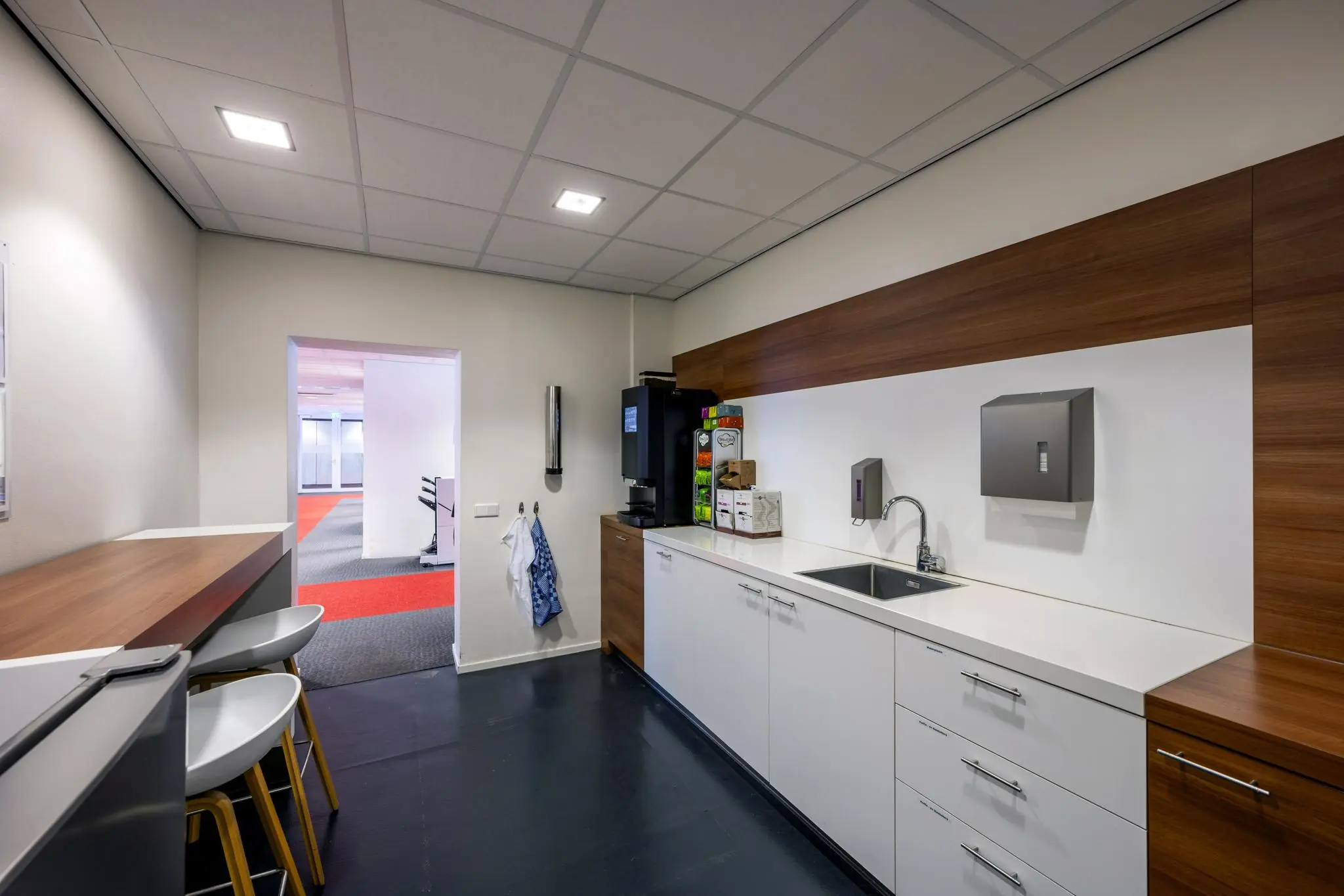 Moderne pantry in een kantoorgebouw aan de Jan Tooropstraat met koffieautomaat, spoelbak en strakke witte kasten.